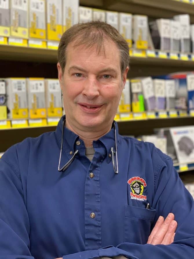 Man wearing blue button-down shirt with Murray's logo in front of merchandise shelving.